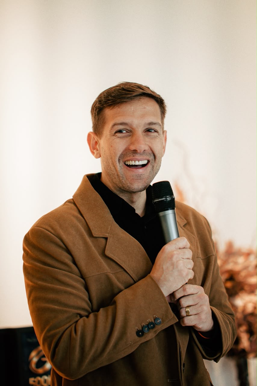Renan Vargas sorrindo ao microfone durante palestra